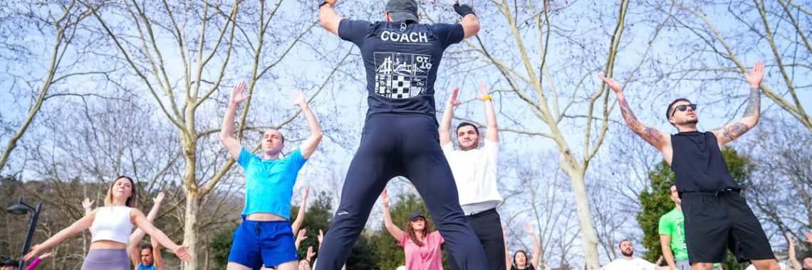 Group exercise session in a sunny Istanbul park led by a fitness coach outdoors.